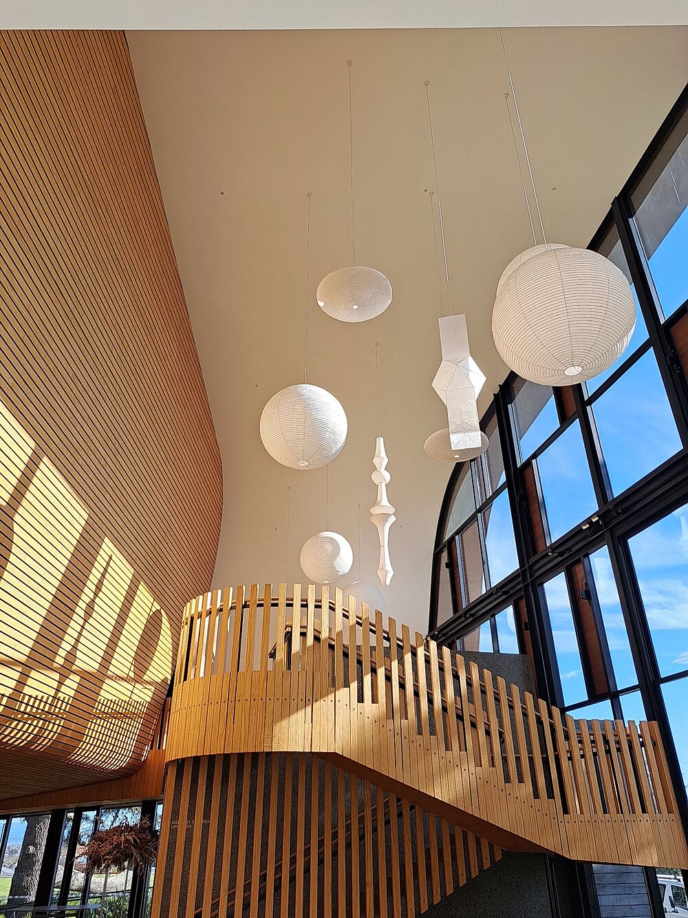 Curved timber-slat ceiling and staircase in a high-stud commercial atrium