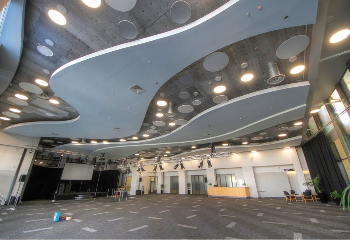 Sculptural suspended ceiling with recessed lighting in a large commercial event space